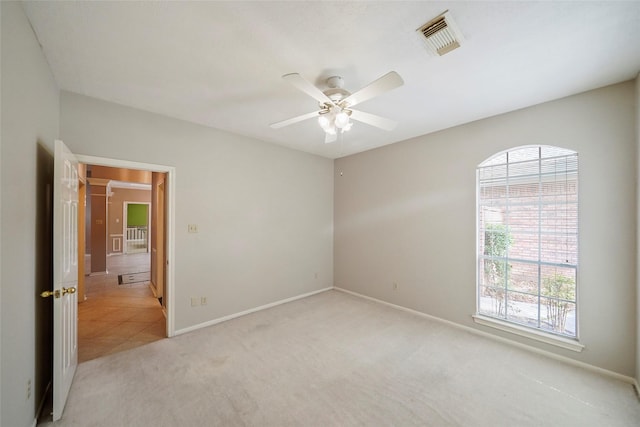 unfurnished room with visible vents, baseboards, light colored carpet, and ceiling fan