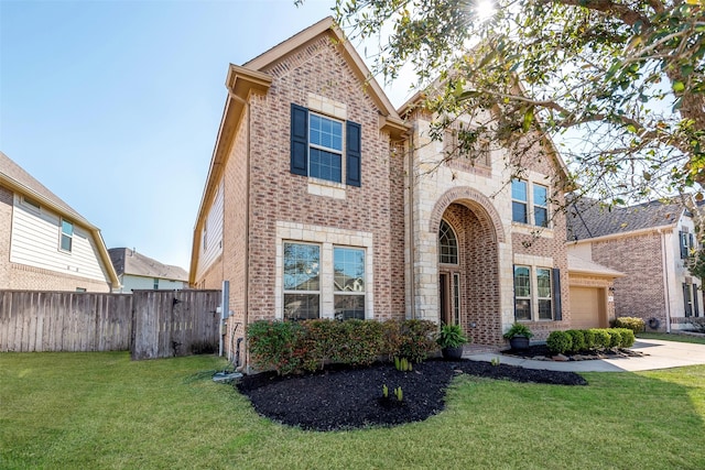 traditional-style home with a front lawn, fence, brick siding, and driveway