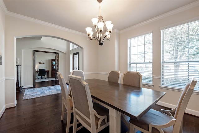 dining area featuring arched walkways, dark wood finished floors, and crown molding