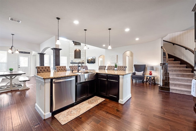 kitchen featuring dishwasher, open floor plan, arched walkways, and a sink