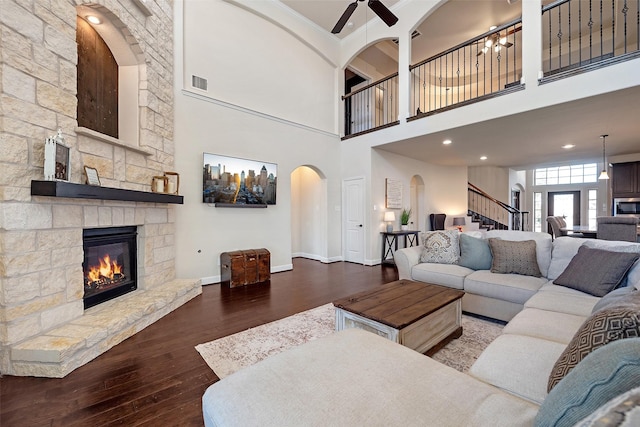 living area with visible vents, baseboards, stairway, a fireplace, and wood finished floors