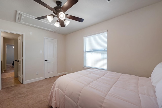 bedroom with attic access, a ceiling fan, baseboards, and light carpet