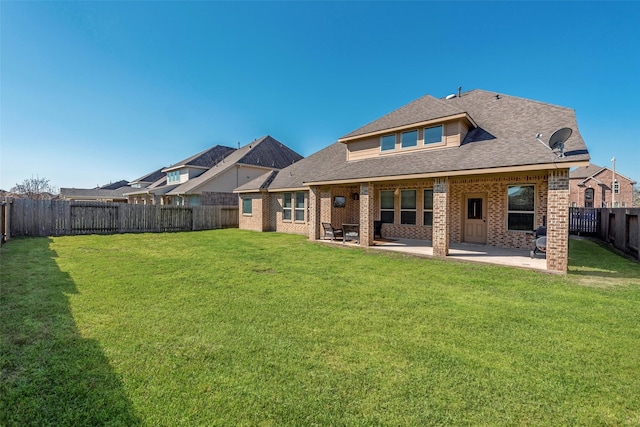 back of house with a patio, a fenced backyard, a yard, roof with shingles, and brick siding