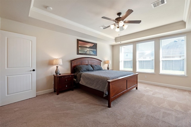 bedroom with a tray ceiling, visible vents, light carpet, and ornamental molding