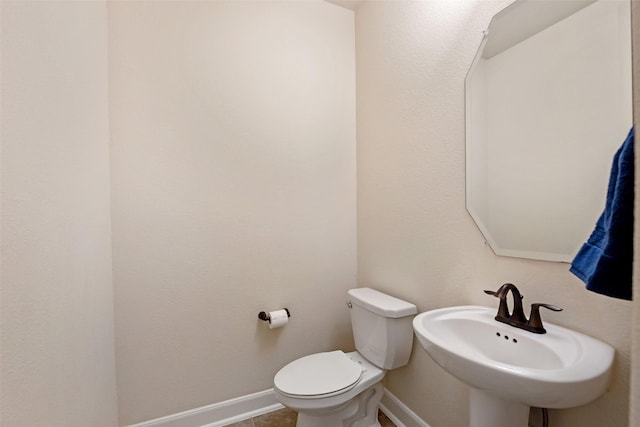 bathroom featuring toilet, baseboards, and a sink