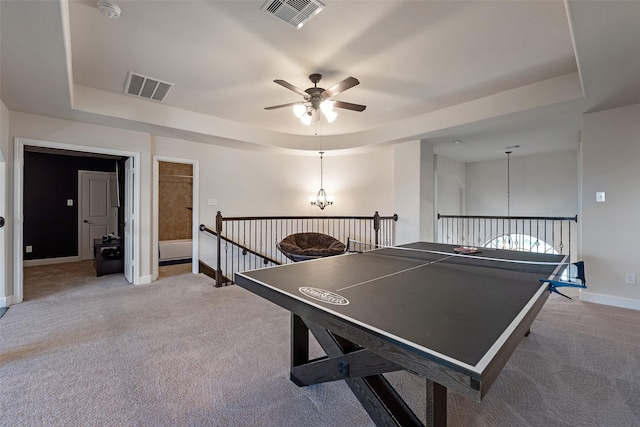 game room with a raised ceiling, baseboards, visible vents, and light carpet