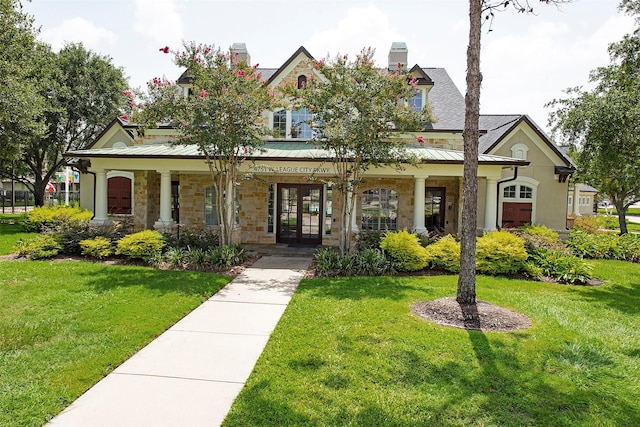 view of front of house with a standing seam roof, a front yard, stone siding, and metal roof