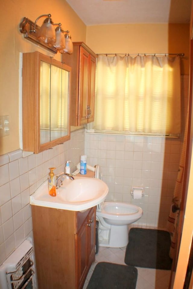 bathroom featuring tile patterned floors, toilet, vanity, and tile walls