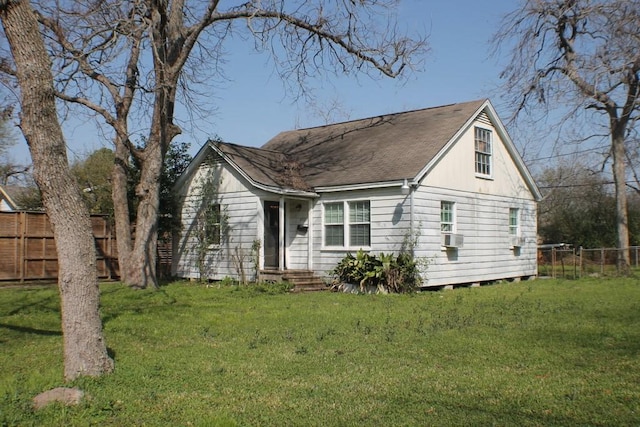 view of front of property featuring roof with shingles, a front yard, and fence