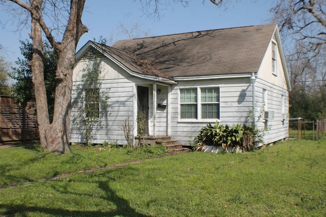 view of front of home with a front lawn, fence, and roof with shingles