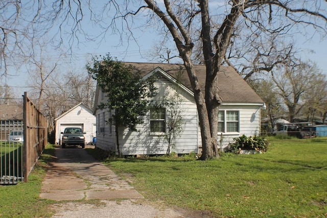 view of side of property featuring fence, a lawn, an outdoor structure, a garage, and driveway