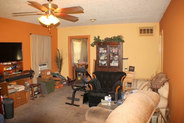 carpeted living room with a textured ceiling, visible vents, and ceiling fan