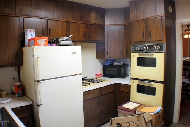 kitchen featuring a sink, white appliances, and light countertops