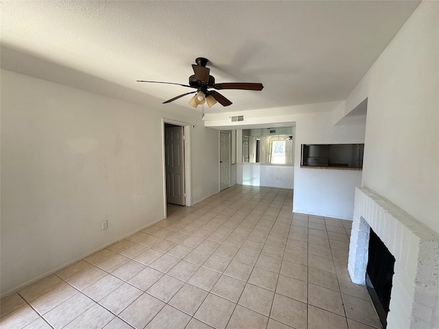 unfurnished living room featuring visible vents, ceiling fan, a fireplace, light tile patterned flooring, and a textured ceiling