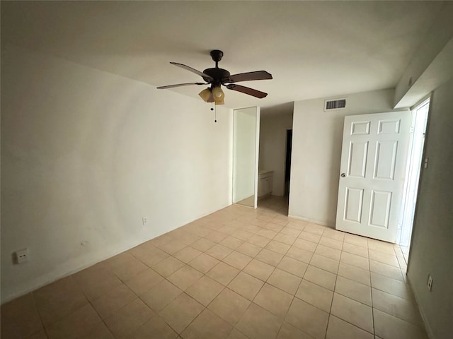 empty room with tile patterned floors, a ceiling fan, and visible vents