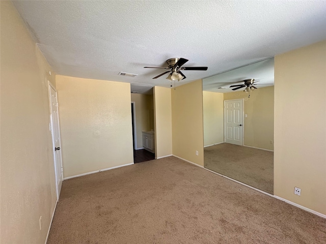 spare room with baseboards, carpet, visible vents, and a textured ceiling