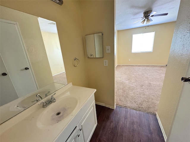 bathroom with vanity, wood finished floors, a ceiling fan, and baseboards