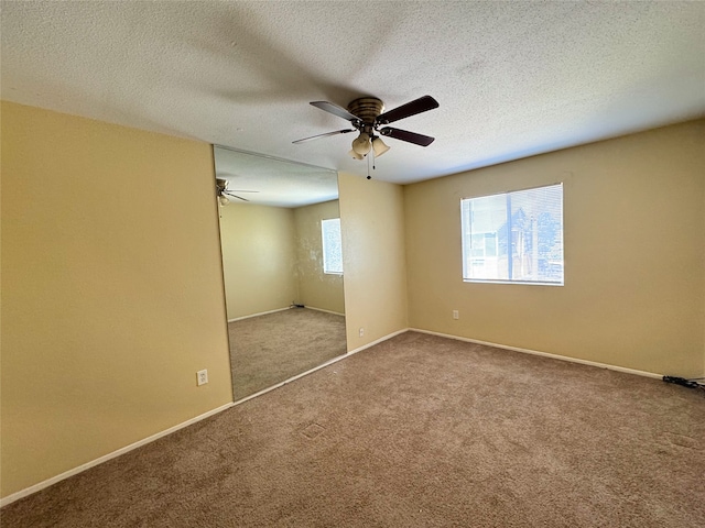 carpeted empty room featuring baseboards, a textured ceiling, and ceiling fan