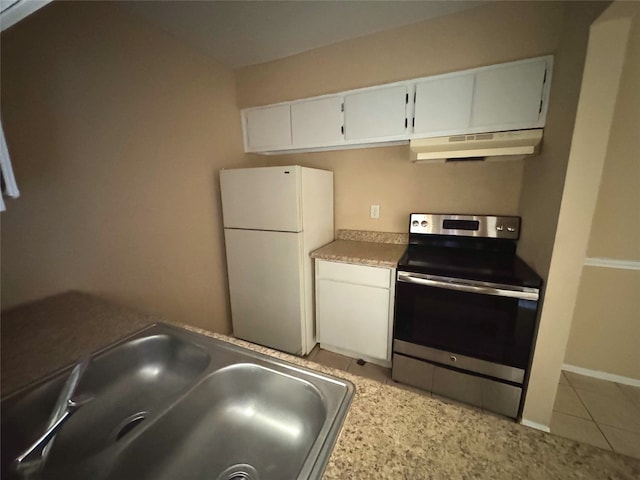 kitchen with under cabinet range hood, stainless steel electric stove, light tile patterned floors, freestanding refrigerator, and a sink