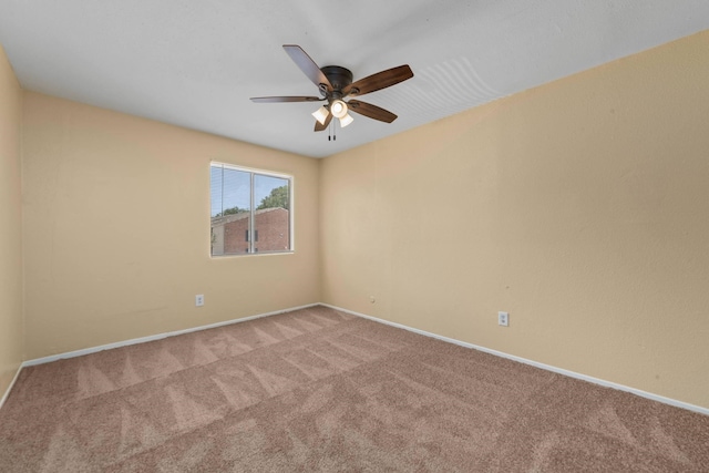 carpeted empty room with ceiling fan and baseboards