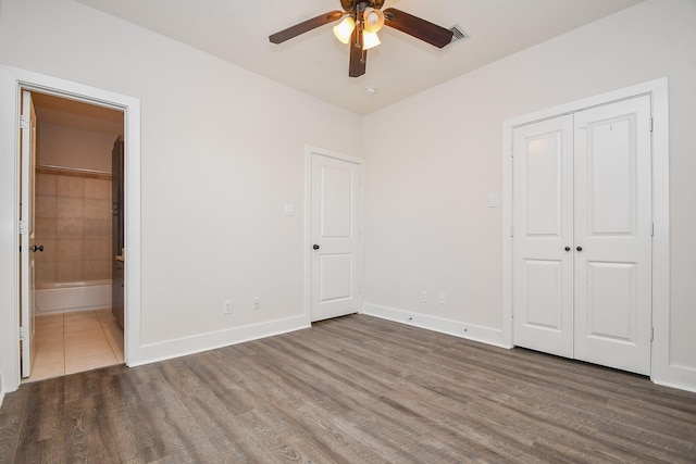 unfurnished bedroom featuring wood finished floors, baseboards, and connected bathroom