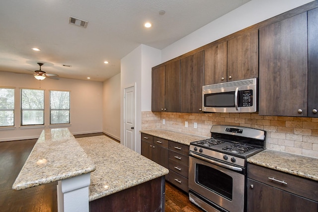 kitchen with dark brown cabinets, stainless steel appliances, visible vents, and decorative backsplash