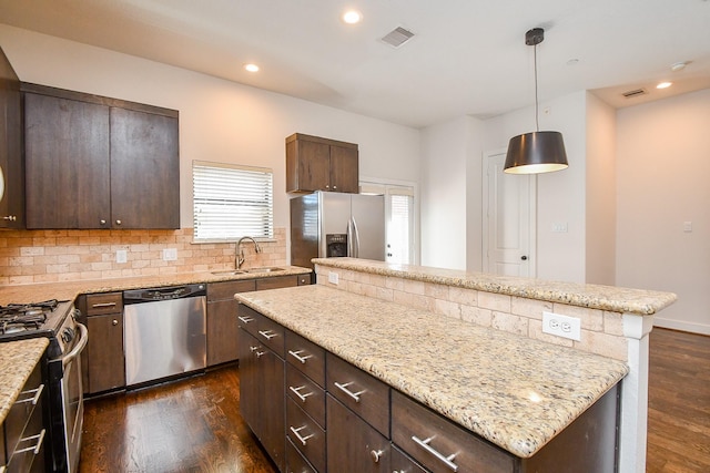 kitchen featuring visible vents, a center island, appliances with stainless steel finishes, dark wood-style floors, and a sink