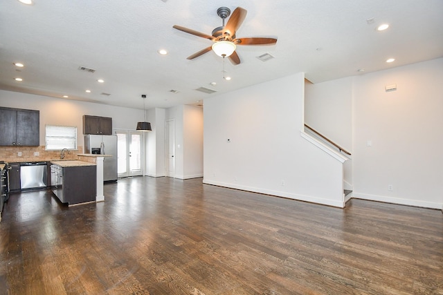 unfurnished living room with a sink, visible vents, dark wood finished floors, and stairs