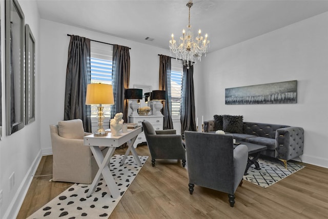 living area with visible vents, baseboards, a notable chandelier, and wood finished floors