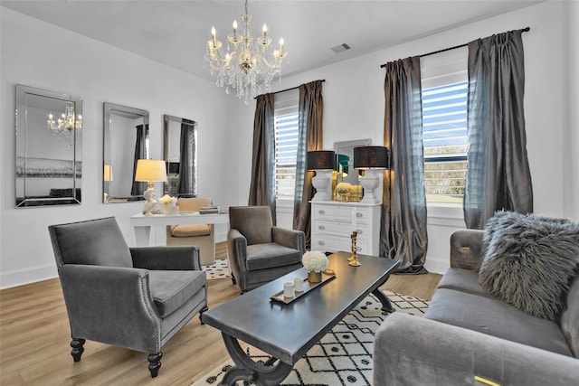 living area featuring light wood-style flooring, baseboards, visible vents, and a chandelier