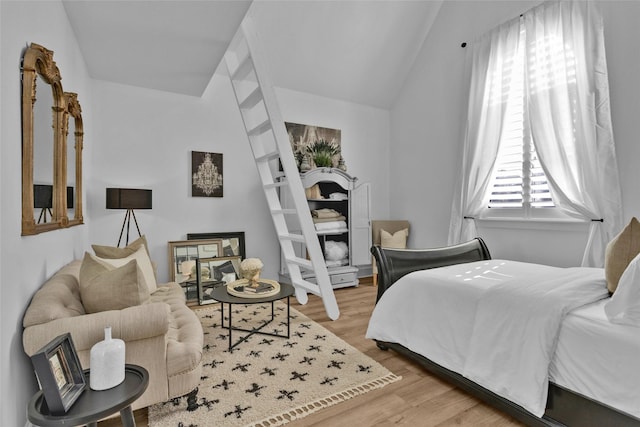 bedroom with light wood-type flooring and vaulted ceiling