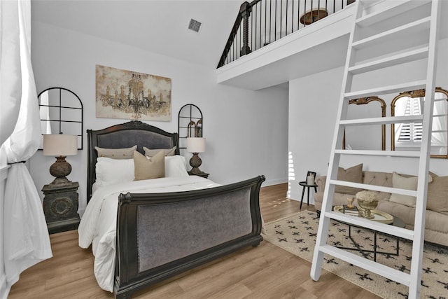 bedroom featuring visible vents, high vaulted ceiling, and wood finished floors