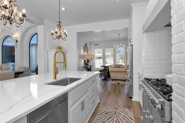 kitchen with a sink, appliances with stainless steel finishes, open floor plan, and an inviting chandelier