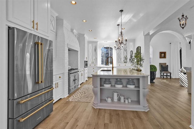 kitchen with open shelves, a sink, stainless steel appliances, arched walkways, and white cabinets