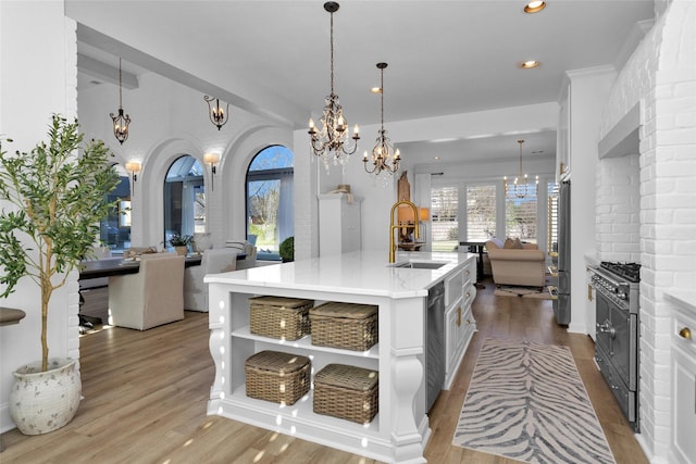 kitchen with premium appliances, open floor plan, open shelves, and a sink