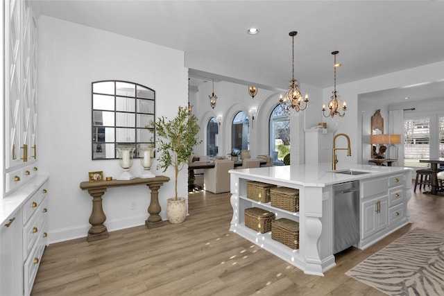 kitchen featuring light wood finished floors, a sink, open shelves, and stainless steel dishwasher