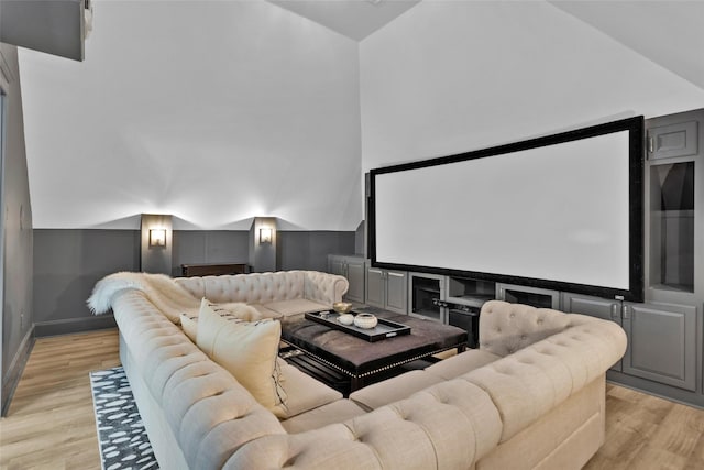 home theater with lofted ceiling, light wood-style flooring, and baseboards