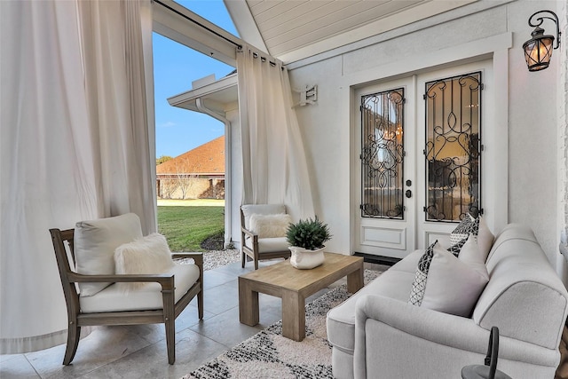 living area featuring french doors, lofted ceiling, and finished concrete flooring