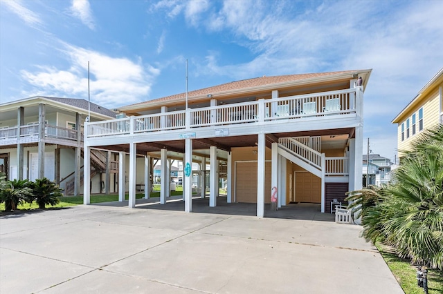 back of house with a carport, concrete driveway, and stairs