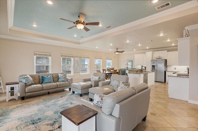 living area featuring a raised ceiling, light tile patterned flooring, a ceiling fan, and visible vents