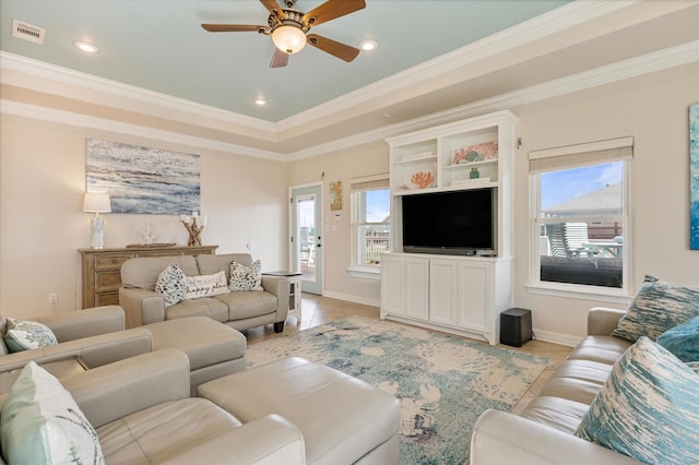 living room with visible vents, a raised ceiling, crown molding, and ceiling fan