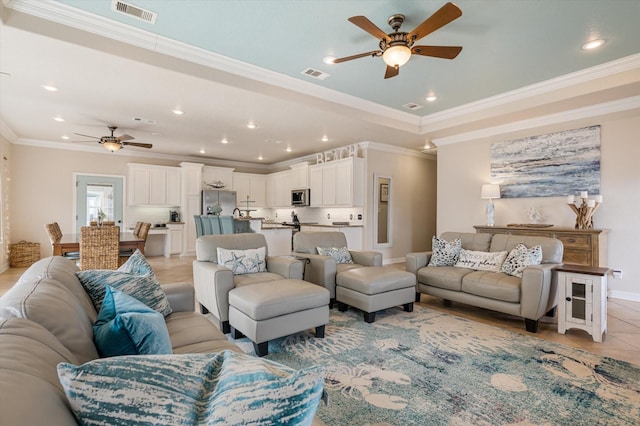 living room featuring visible vents, a tray ceiling, and a ceiling fan