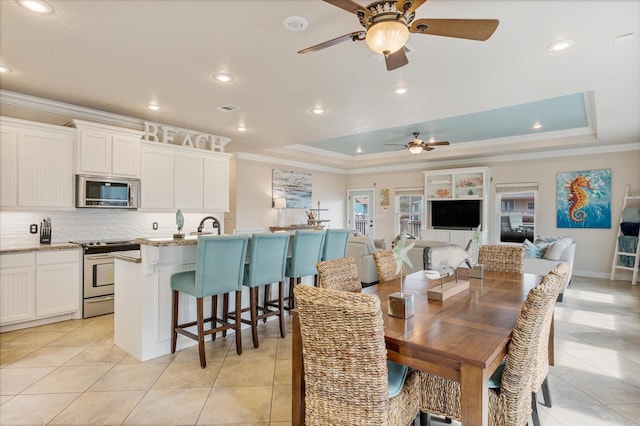 dining room with a raised ceiling, a ceiling fan, visible vents, and ornamental molding