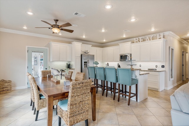 dining space featuring visible vents, crown molding, baseboards, ceiling fan, and light tile patterned floors