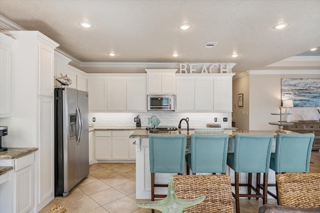 kitchen featuring a breakfast bar area, ornamental molding, decorative backsplash, appliances with stainless steel finishes, and white cabinetry