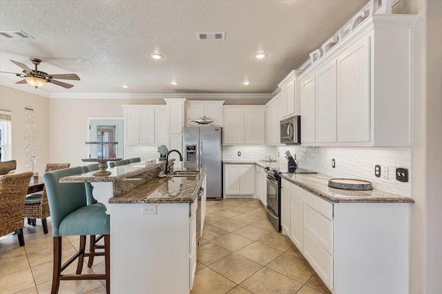 kitchen featuring a breakfast bar, visible vents, appliances with stainless steel finishes, and a sink