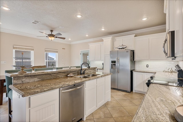 kitchen featuring ceiling fan, a center island with sink, stainless steel appliances, white cabinetry, and a sink