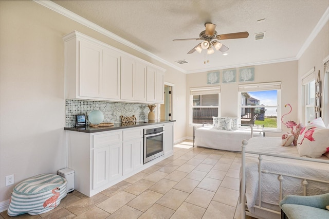 kitchen with a ceiling fan, white cabinets, open floor plan, stainless steel oven, and tasteful backsplash