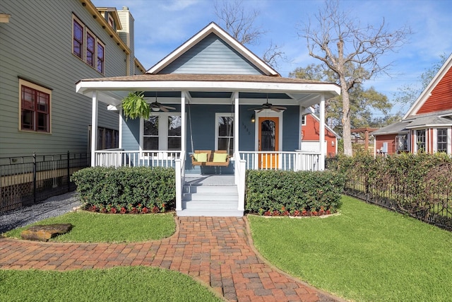 view of front of house with a front lawn, fence, a ceiling fan, and covered porch