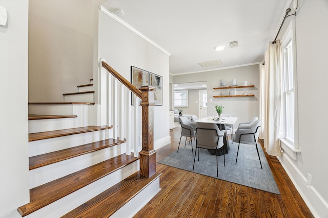 dining space featuring dark wood-style floors, visible vents, baseboards, stairs, and crown molding